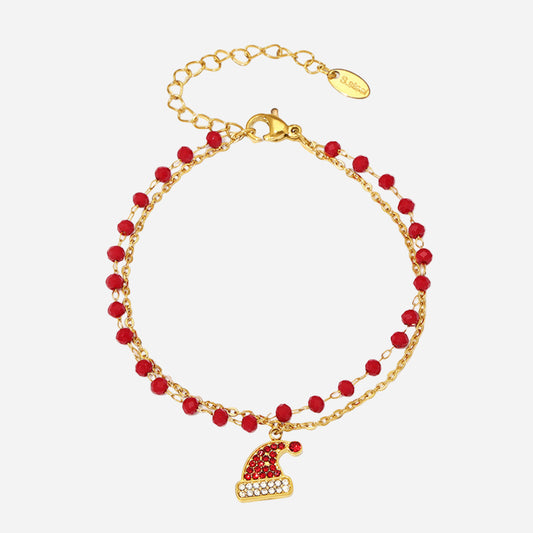 Gold bracelet with red beads and a heart charm on a white background