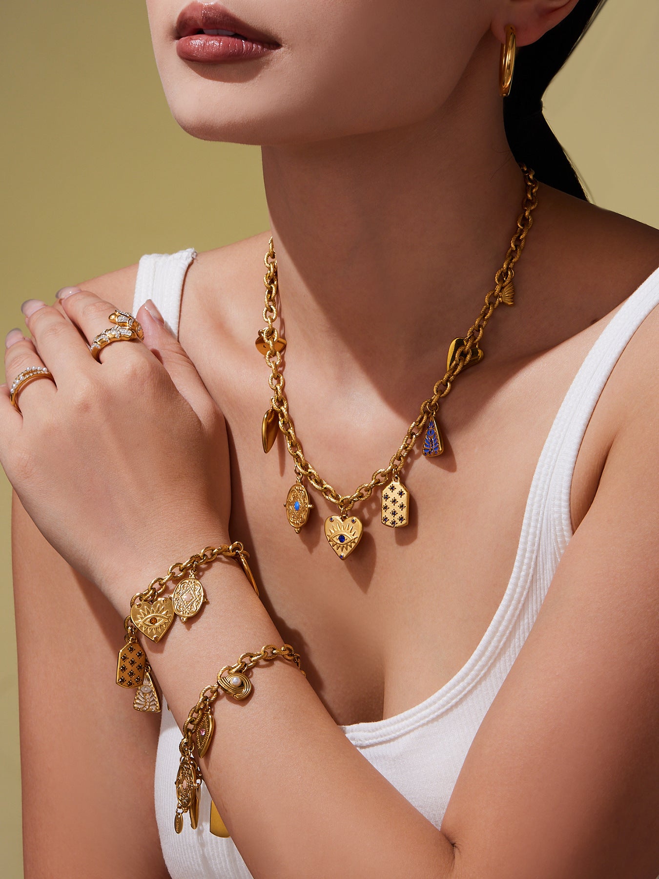 Model wearing gold evil eye charm bracelet layered with necklaces, waterproof stainless steel jewelry