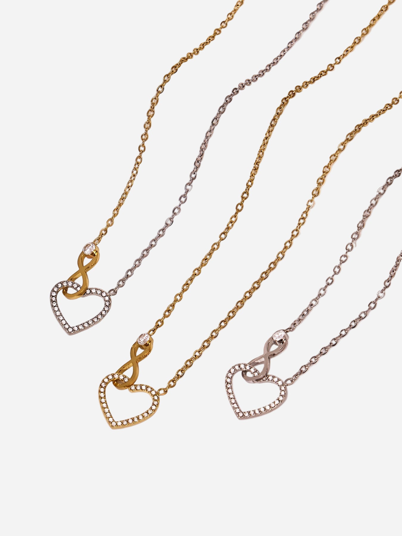 Three gold necklaces with heart and infinity pendants on a white background