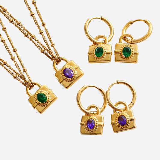 Gold jewelry set with lock-shaped pendants featuring colored stones on a white background