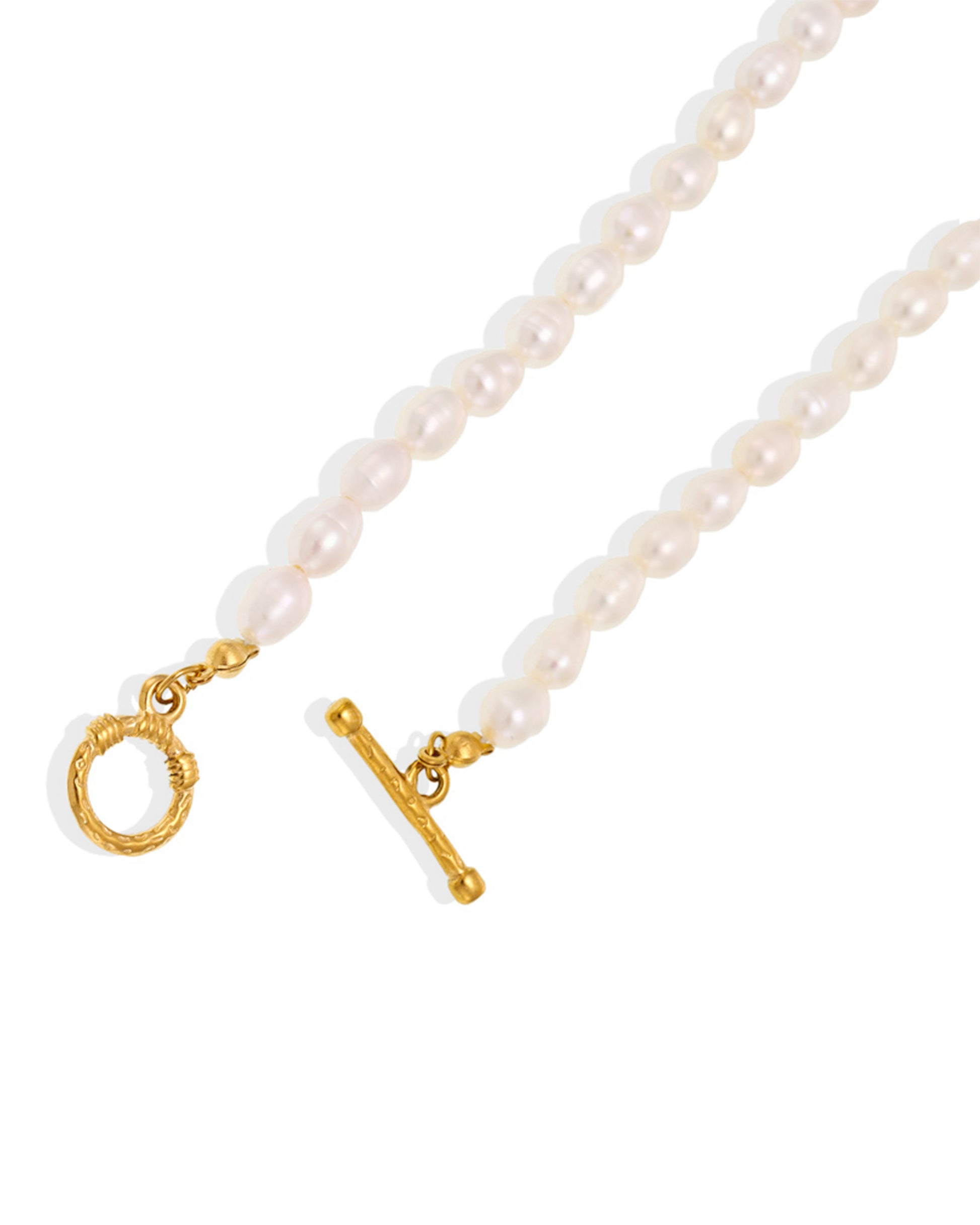 Gold and pearl bracelet resting on soft fabric in warm light setup