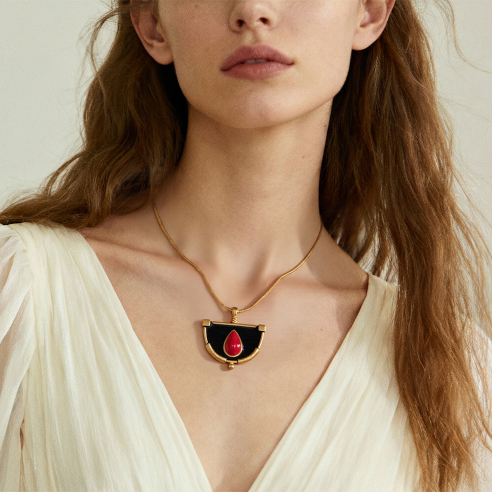 Model wearing gold snake chain necklace with red enamel fan pendant charm, minimalist statement jewelry.