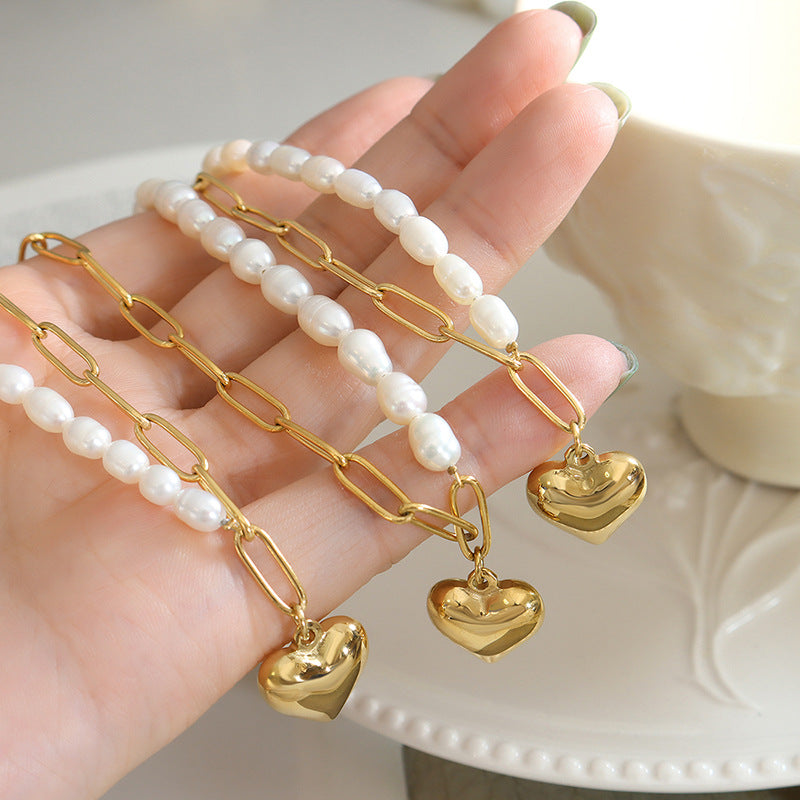 Close-Up of Model Holding Baroque Freshwater Pearl Heart Necklace – Gold Chain Detail
