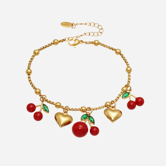 Gold bracelet with heart and cherry charms on a white background