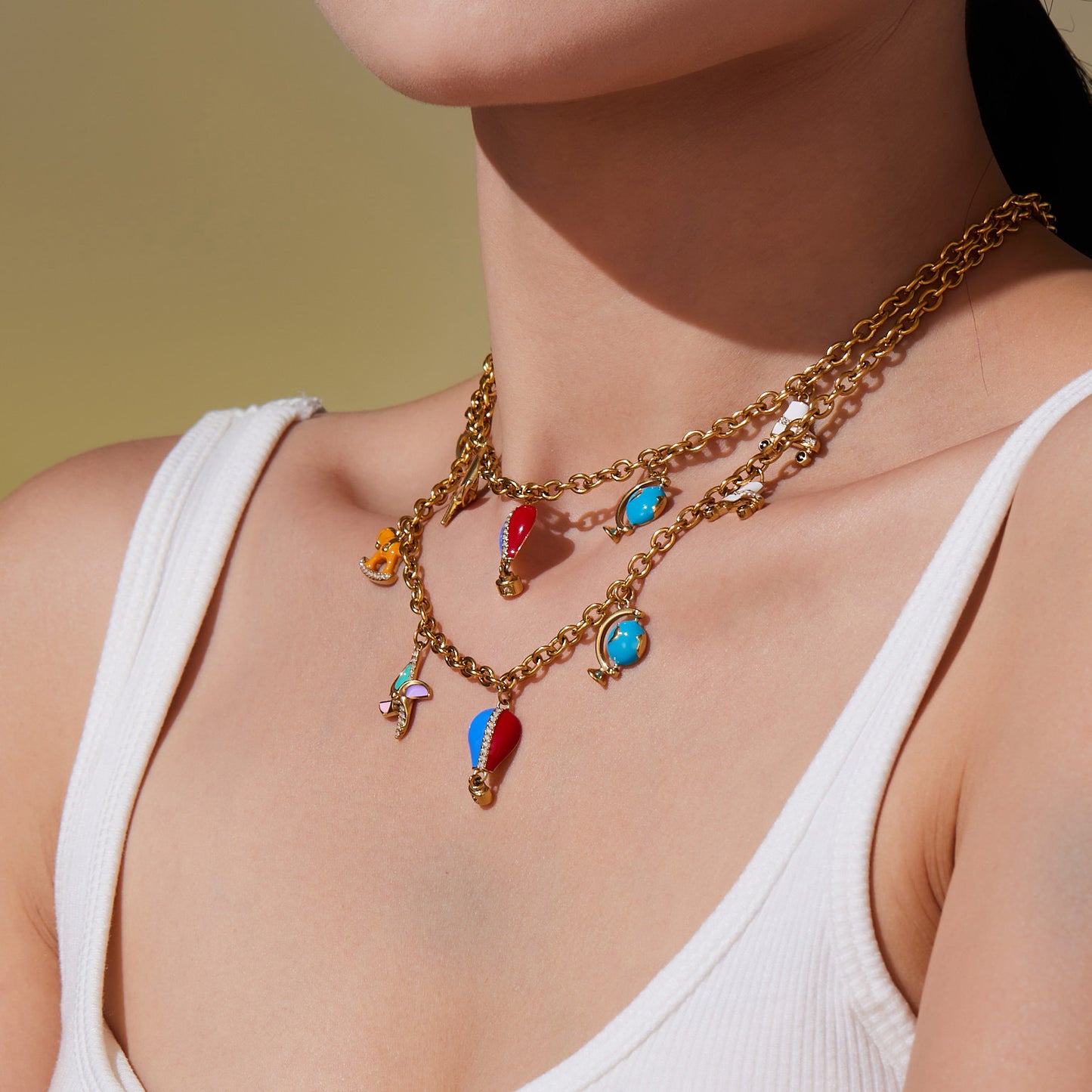 Close-up of stainless steel charm pendant necklace layered with other gold necklaces