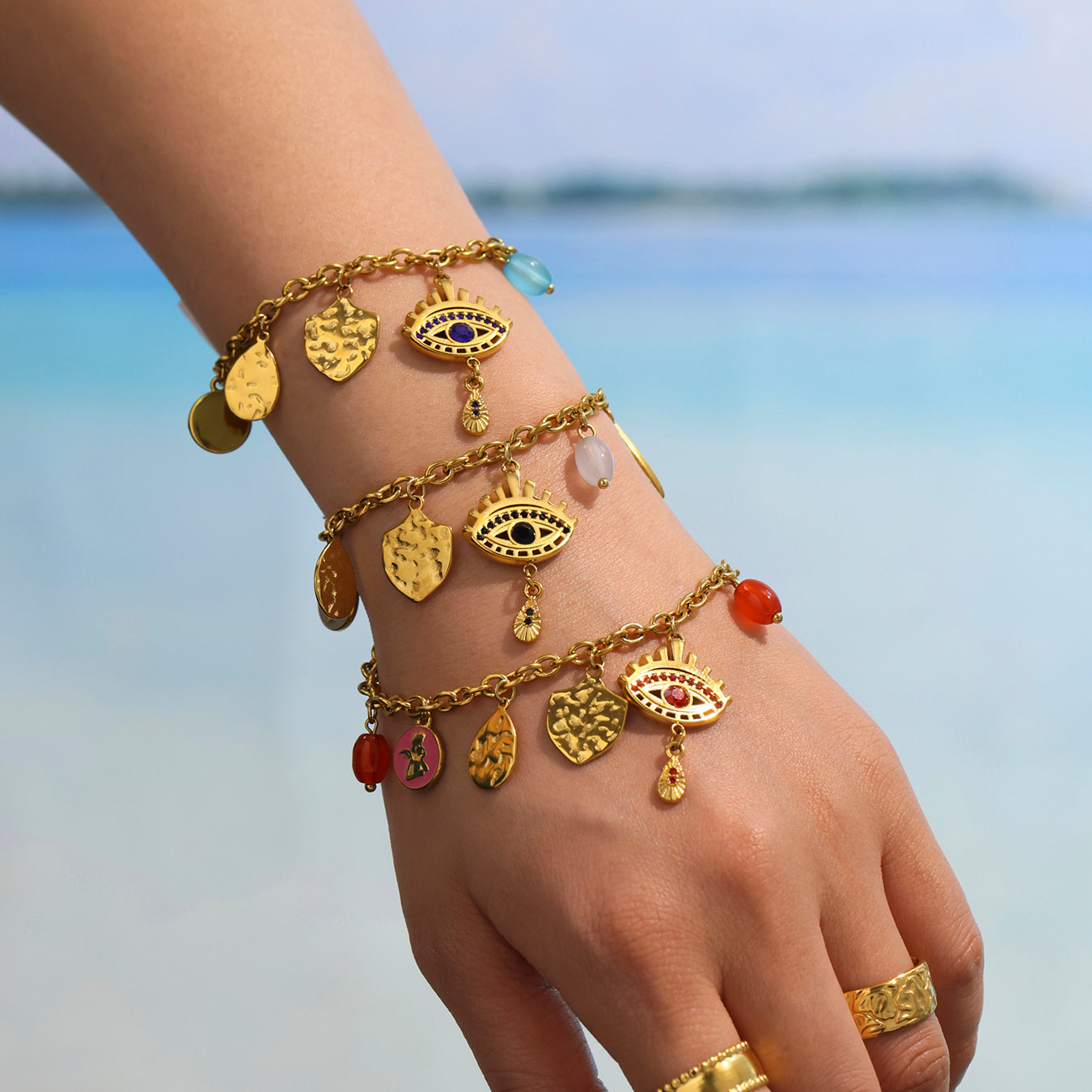 Model layering Black Mystic Evil Eye Bracelet with other pieces – ocean breeze background, stackable jewelry
