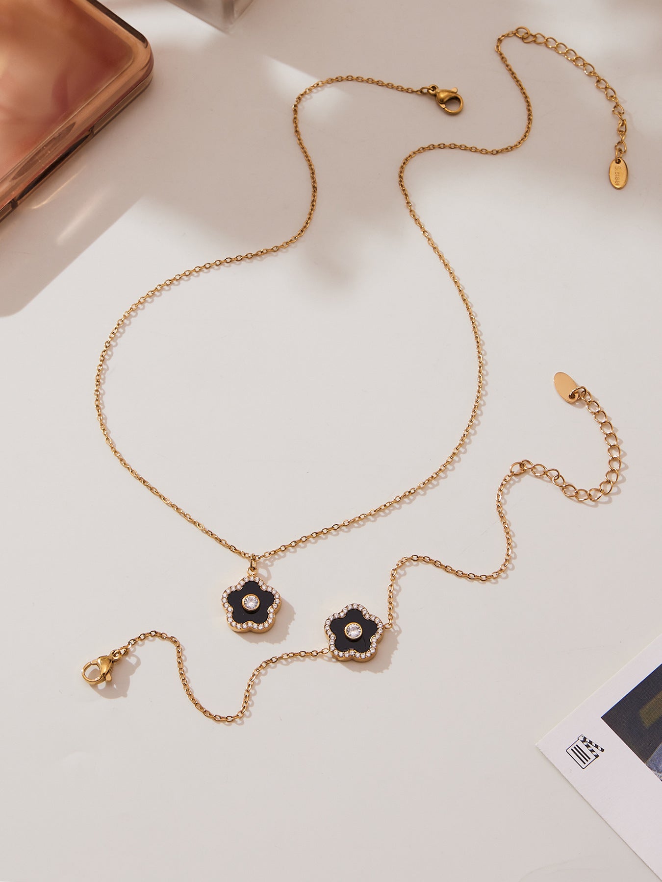 Gold necklace with floral pendants on a light background